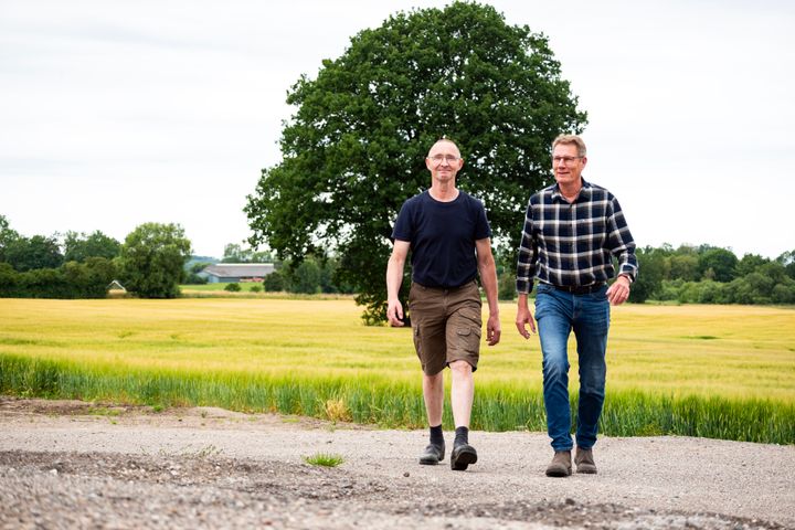 To mnd gr udendrs foran et stort tr og en mark.